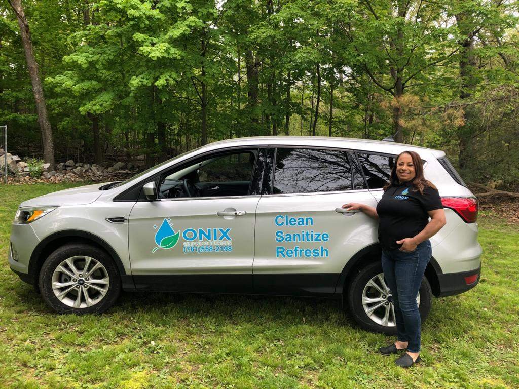 A woman standing next to a silver Ford Escape in Boston.