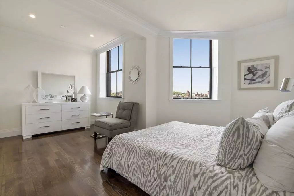 A Boston bedroom with hardwood floors and a large window.