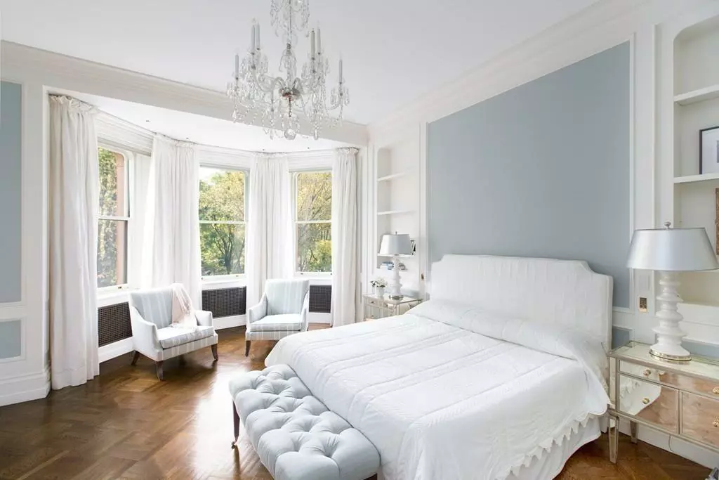 A clean white bedroom with blue walls and a chandelier.