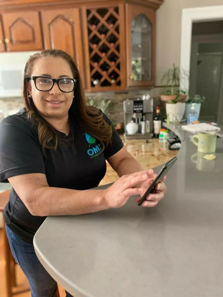 A woman holding a cell phone in front of a kitchen counter in Boston.