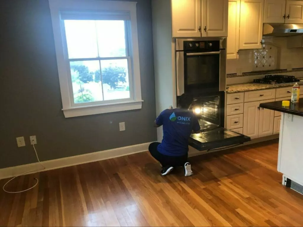 A man providing oven cleaning services in a kitchen.