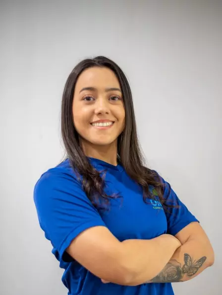A young woman in a blue shirt with her arms crossed offering cleaning services in Boston.