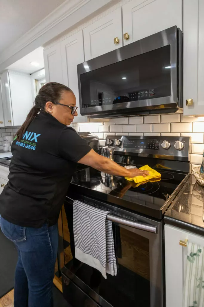 A woman cleaning a stove in a kitchen in Boston.