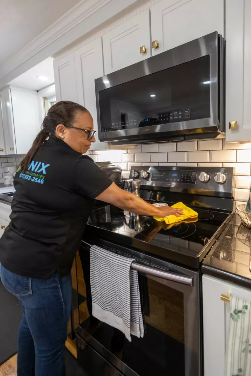 A woman cleaning a stove in a kitchen in Boston.