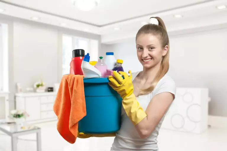 Best Cleaning Products for Kitchen; an image of a woman holding a bucket filled with cleaning supplies