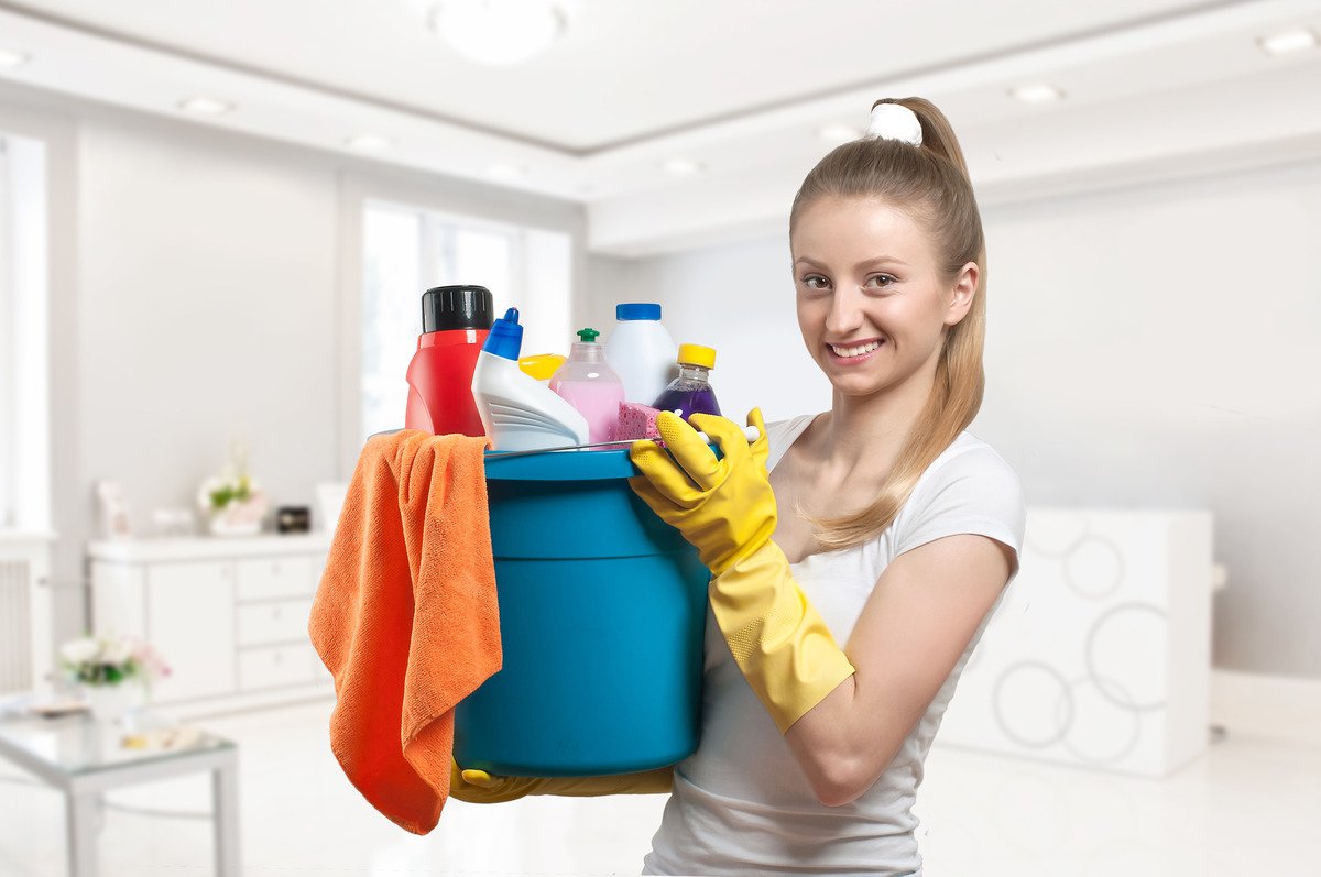 Best Cleaning Products for Kitchen; an image of a woman holding a bucket filled with cleaning supplies