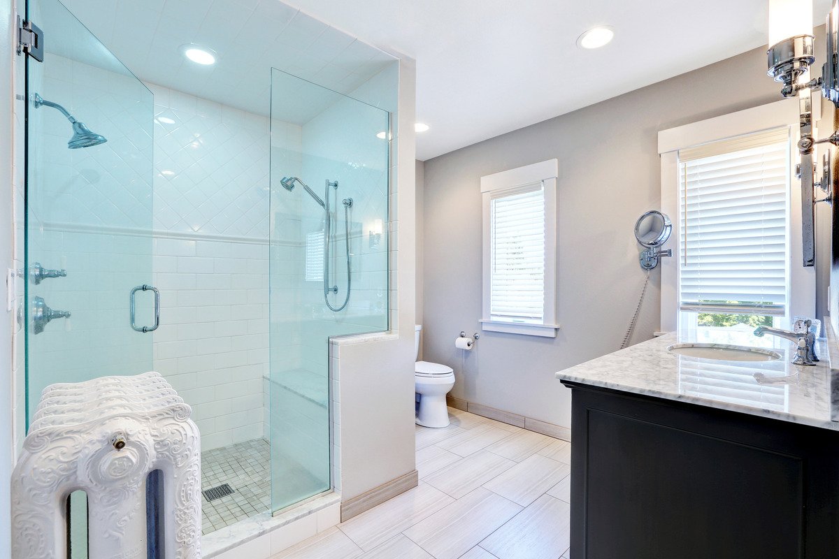 an image of a roomy bathroom featuring a light blue shower glass door; clean glass shower doors
