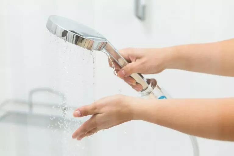 a cropped image of a woman's hands holding a shower head