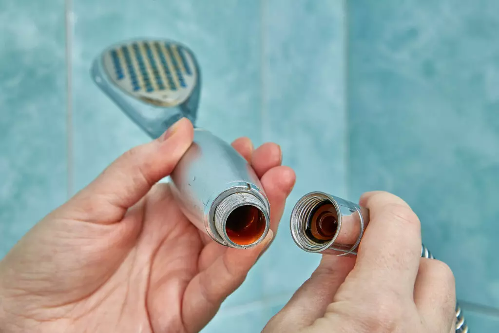 an image of hands disconnecting a showerhead