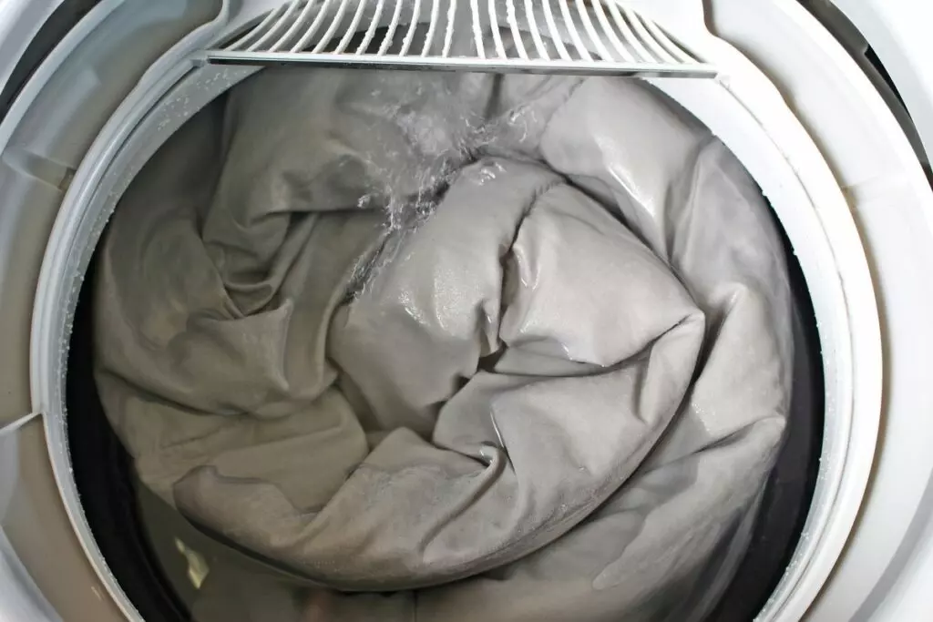 close up image of a washing machine compartment filled with a large load of quilts