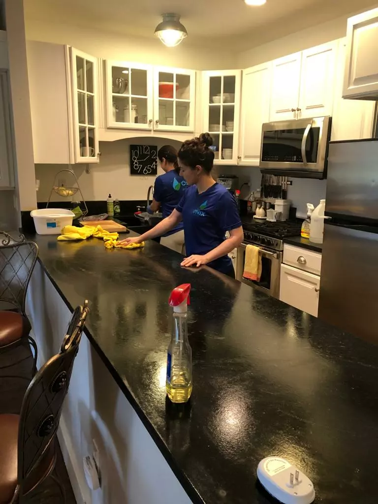 Two cleaners tidying a kitchen counter top.