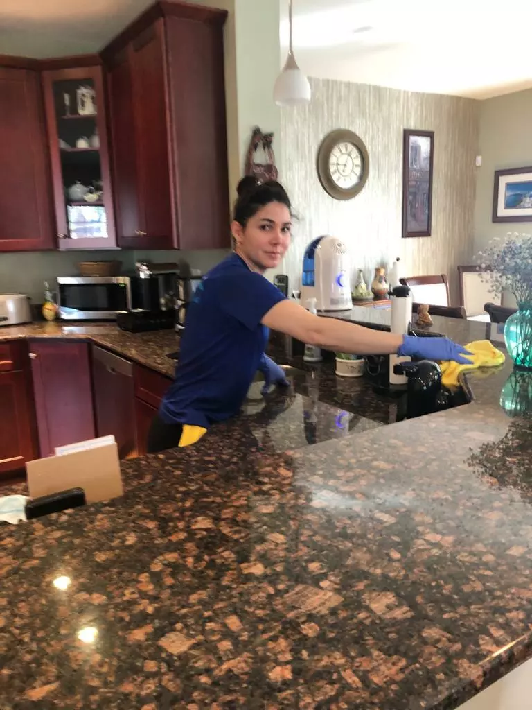 A woman from a cleaning company in Boston diligently cleans a kitchen counter top.