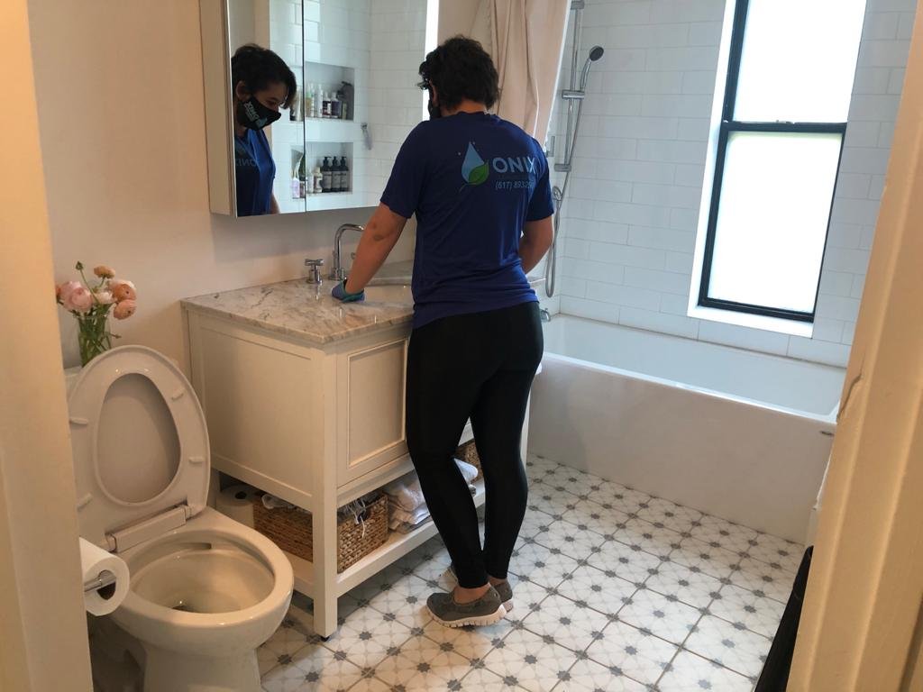 clean your bathroom; a female janitorial staff member of onix, wearing a uniform, is diligently cleaning the laboratory sink in a bathroom