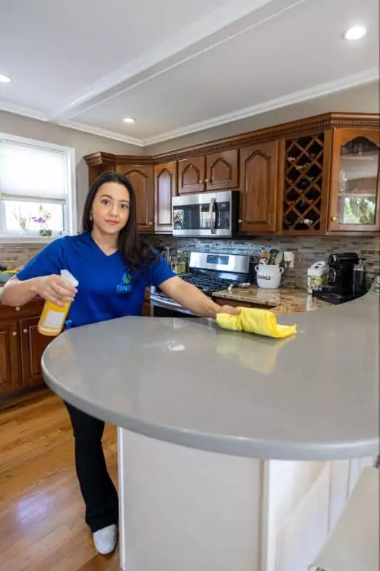 A woman cleaning a counter top in a kitchen in Boston.