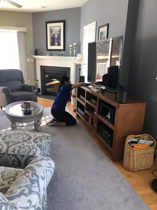 A Boston man cleaning a living room with a TV.