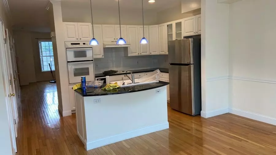 A pristine kitchen with white cabinets and hardwood floors, ideal for Airbnb hosting.