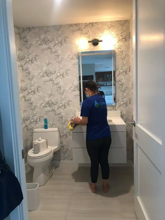 A woman in a blue shirt meticulously cleaning a bathroom—professional bathroom cleaning service in Boston.
