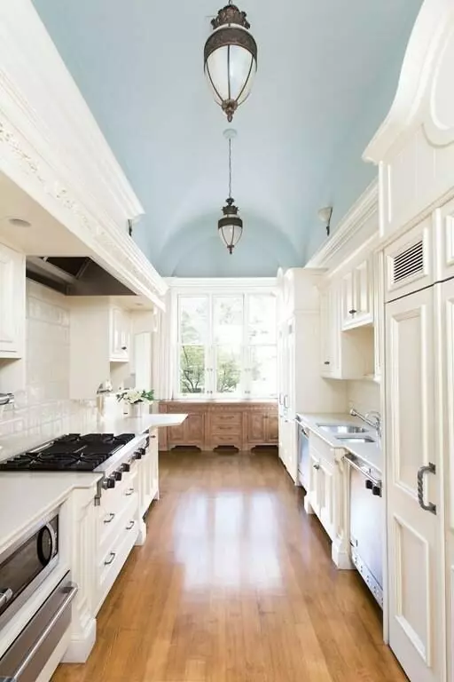 An Airbnb kitchen with a white color scheme, blue ceilings, and warm wood floors. airbnb cleaning service in boston