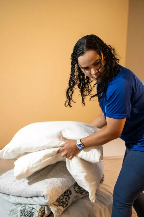 A woman holding a pillow while tidying up her apartment.