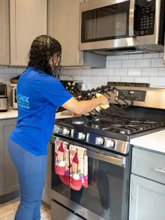 A woman cleaning a stove in a kitchen before moving out.