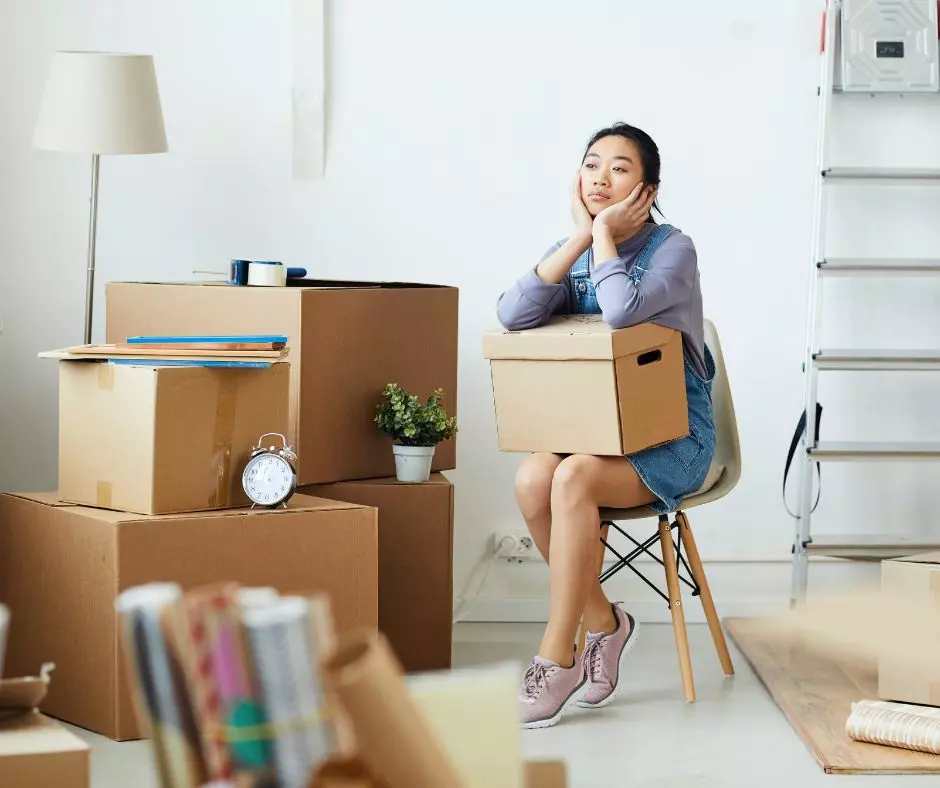 A woman sits on a chair in a room with moving boxes, preparing for a move in or move out cleaning service in Boston.