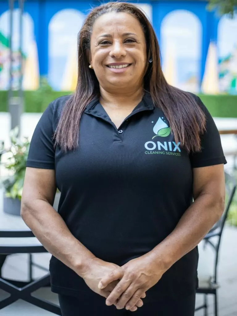 A woman wearing a black polo standing outside, holding standard cleaning templates.