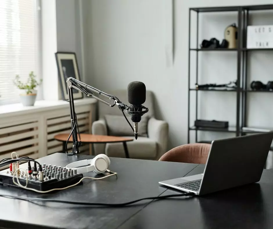 A modern podcast setup featuring a microphone on a swing arm, headphones, a mixer, and a laptop on a desk in a stylish room with studio cleaning templates.