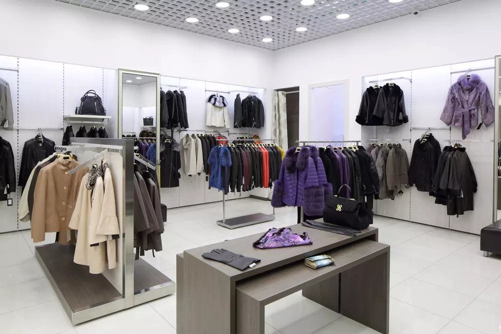 A clothing store display with various coats, jackets, and accessories neatly arranged on racks and shelves showcases our premium services.