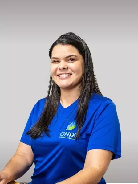 Smiling woman wearing a blue "Onix Cleaning Services" shirt poses in front of a plain background, as if ready to attend an art gallery opening.