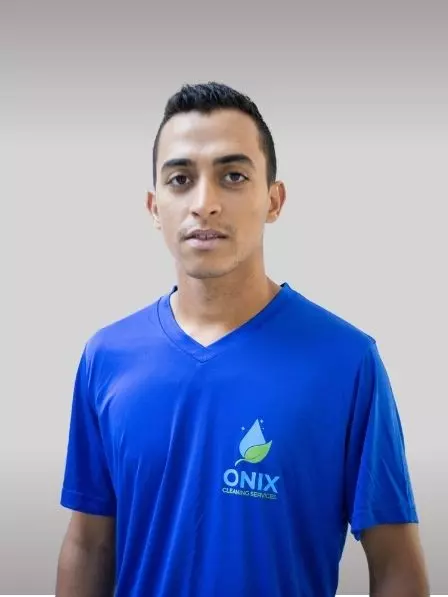 A man wearing a blue "Onix Cleaning Services" shirt stands against a plain gallery background, looking at the camera.