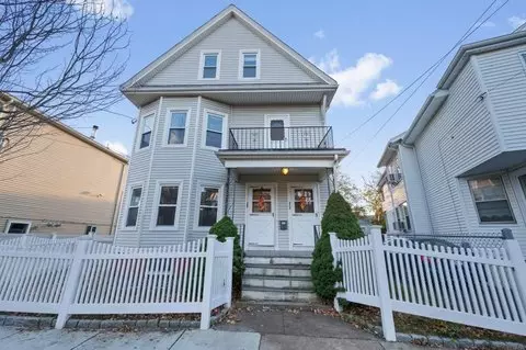 Nestled in the charming community of Winthrop, MA, this three-story house features light gray siding and a quaint front porch, all beautifully enclosed by a classic white picket fence.